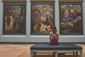 Woman at a museum sitting on a bench looking at paintings